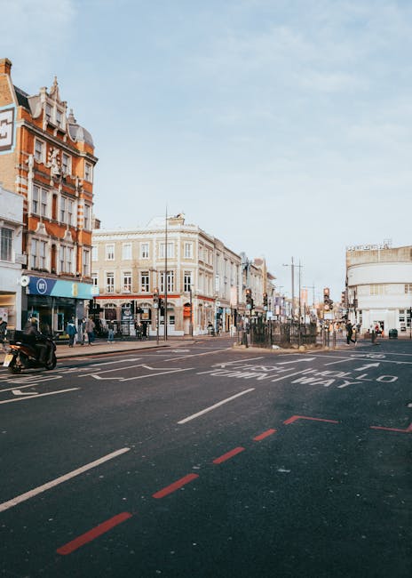 A street scene on Ilford High Road near Ilford Station taken during daytime, featuring a mix of traditional and modern buildings with brick facades, large windows, and decorative architectural details